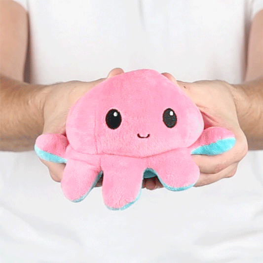 A person holding a TeeTurtle Reversible Octopus Plushie (Aqua + Pink).