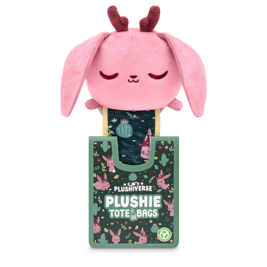 A Plushiverse Fearsome Jackalope plushie tote bag with pink ears and a serene expression, protruding from a decorative green box labeled